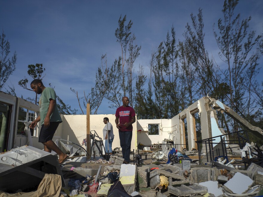 George Bolter (left) and his parents walk through the remains of his home, which was destroyed by Hurricane Dorian in the Pine Bay neighborhood of Freeport, Bahamas. Rescuers trying to reach drenched and stunned victims fanned out across a blasted landscape of smashed and flooded homes Wednesday.