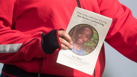 a funeral service card bearing the likeness of Tyre King, carried by a mourner outside the First Church of God in Columbus on September 24, 2016.