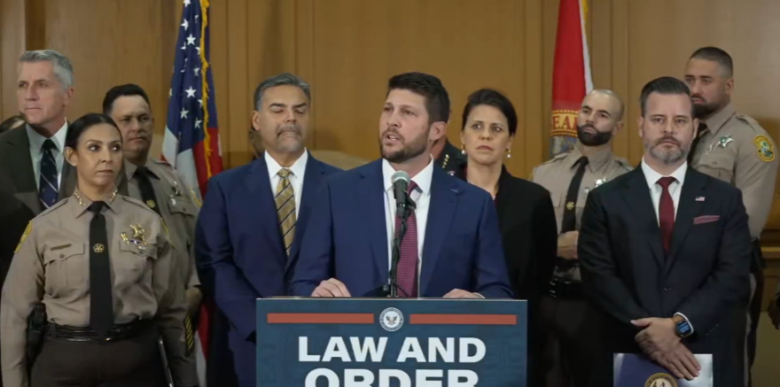 Florida Attorney General James Uthmeier speaks at a podium bearing a “Law and Order” sign during a news conference.