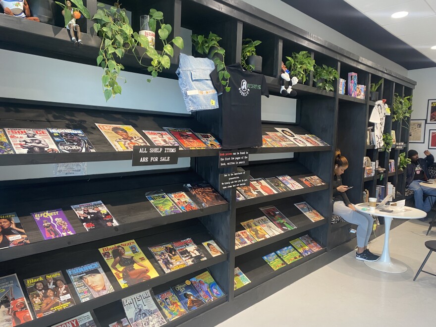 Plants overhang shelves that include a selection of comics, vintage JET, hip-hop magazines, and children’s books found with Archive CLT.