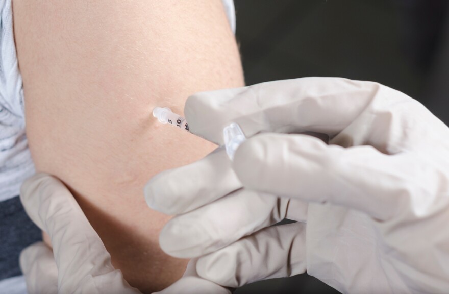 Medical professional wearing gloves uses a syringe to give vaccine to a patient