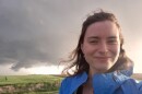 Meteorologist Amanda Wagner standing in front of a storm cloud in the fields of Kansas.
