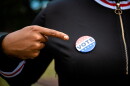 Woman Pointing At A Vote Button Pinned To Her Sweater