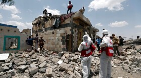 Yemeni Red Crescent workers and civilians stand at the site of an air raid in the Arhab area, around 13 miles north of Sanaa, on Aug. 23, 2017, where a Saudi-lead coalition has been bombing Iran-backed Huthi rebels. (Mohammed Huwais/AFP/Getty Images)