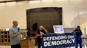 Harry Dunn is standing behind a podium, speaking to supporters about Jan.6