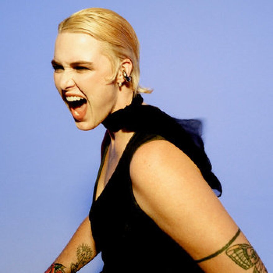 A blonde woman looking to the side with her mouth open wide, maybe screaming into the void.