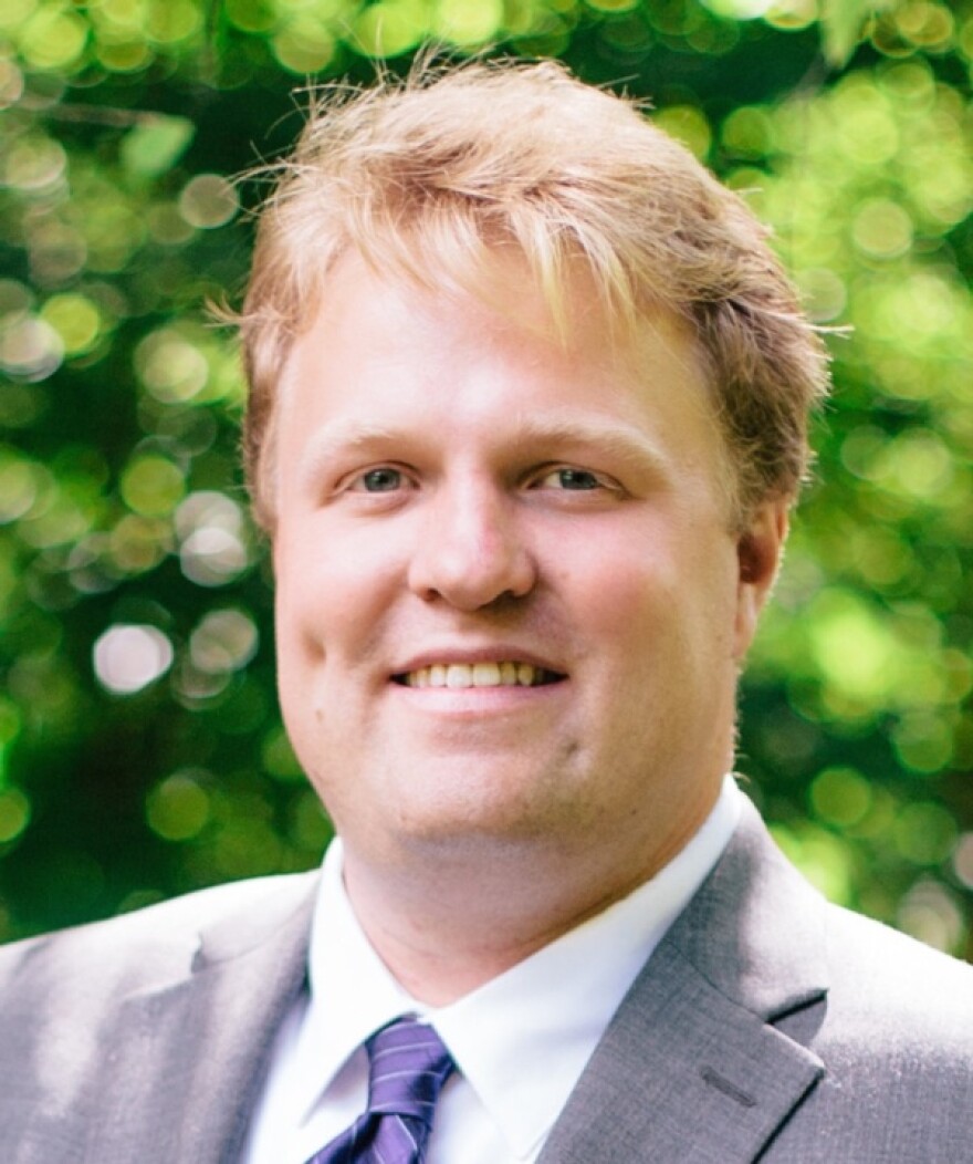 headshot of Seth Jacobson, a blonde white man. He is smiling and wearing a suit.