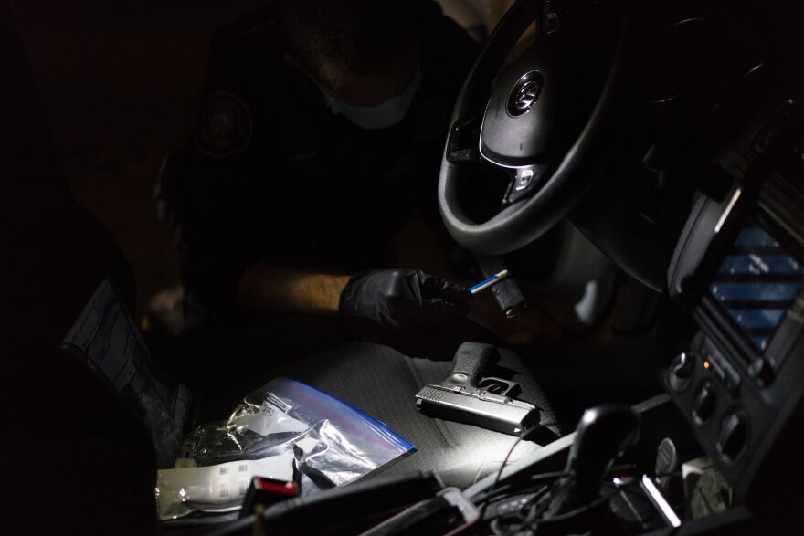 Officer Patrick Murphy swabs a handgun that he and gang enforcement officers found in a car with three people in front of a high school homecoming football game in Portland, Ore.