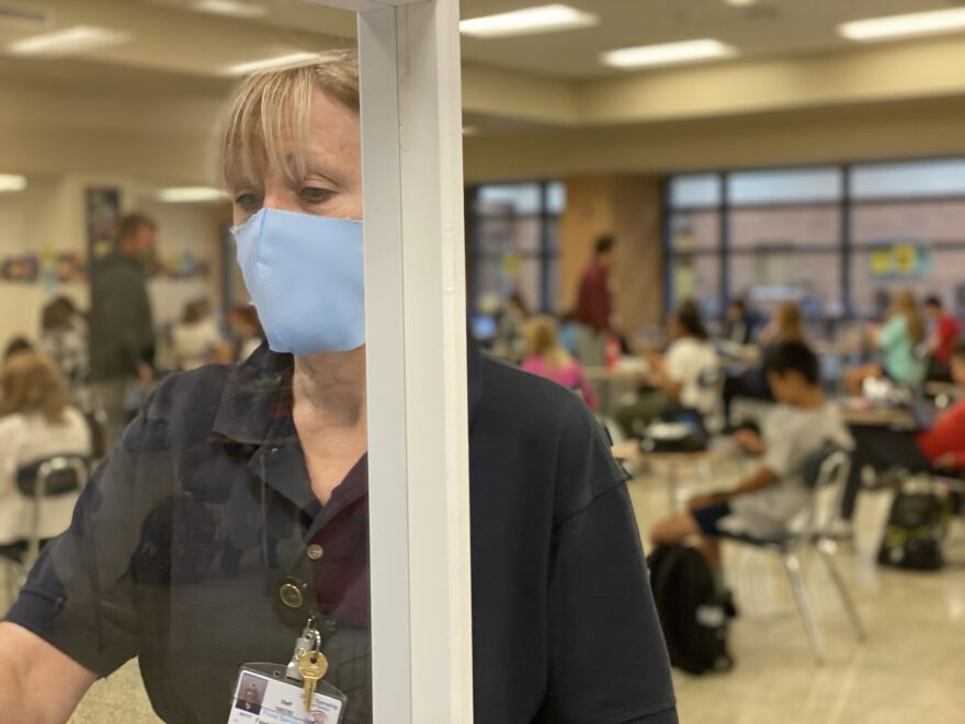 School cafeteria worker Fawn Kunkle-Tucci checks out a student who is getting lunch while in the background eighth grade students sit at desks to eat.