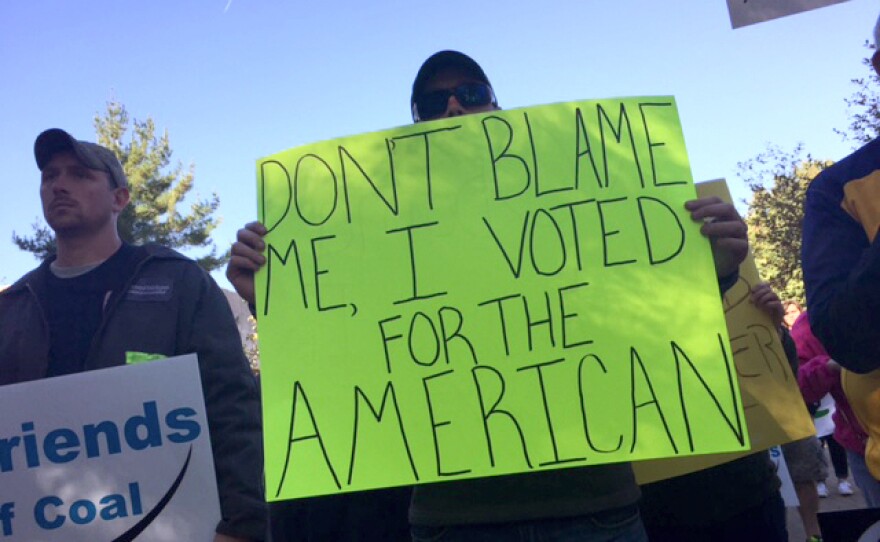 A protester in West Virginia holds up a sign that says, "Don't blame me, I voted for the American."