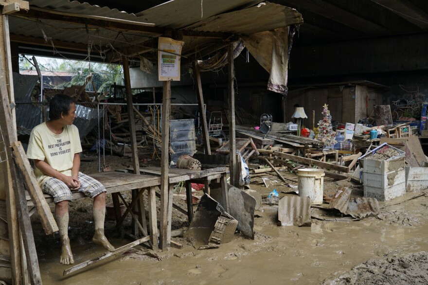 A man sits beside remnants of damaged homes in Talisay city, Cebu province, central Philippines on Dec. 17.