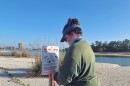 Woman on beach stands near do not enter important nesting area sign