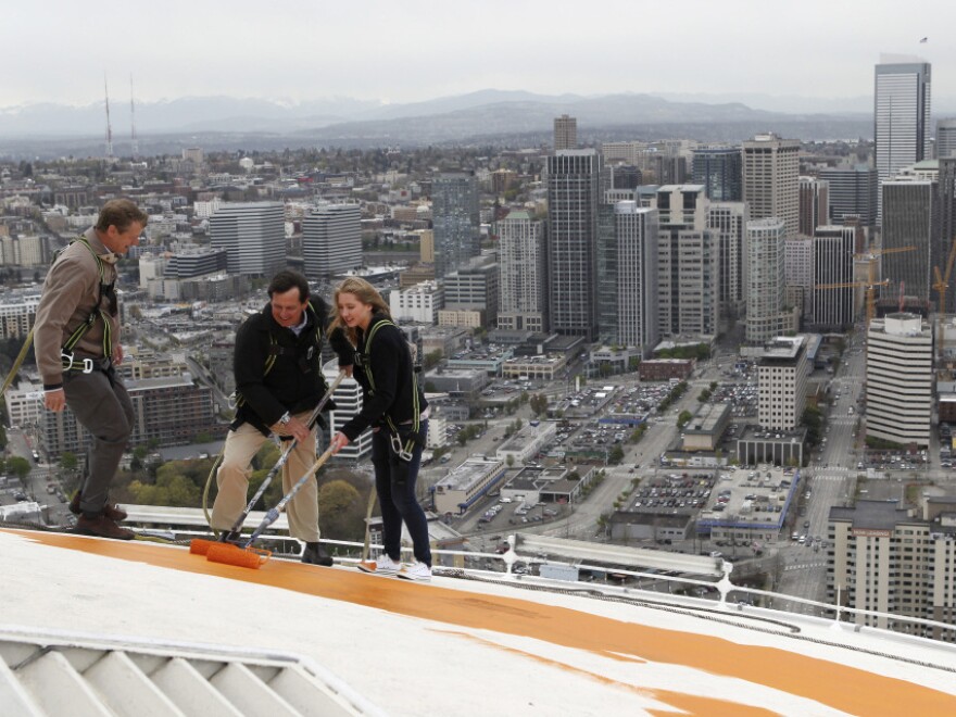 Jeff Wright (center), whose family owns the Space Needle, starts the repainting of the iconic structure on Tuesday with his 15-year-old daughter, Mauren, and Space Needle board member Stuart Rolfe. The new color is the original color, dubbed "galaxy gold."