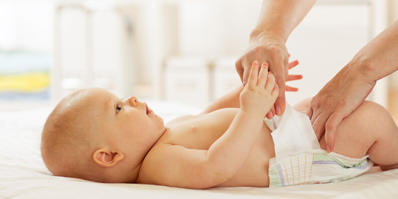 An adult puts a new diaper on a baby.