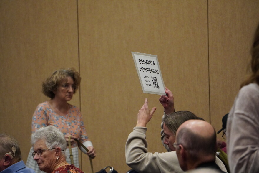 An attendee at the data center informational meeting holds a sign reading, "demand a moratorium." Many municipalities have requested a statewide moratorium on data center development to update their zoning codes and learn more about the impacts of data centers. 