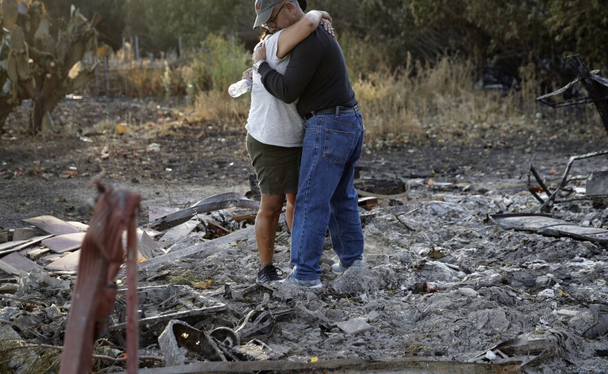 Justo and Bernadette Laos hug while looking through the charred remains of the home they rented that was destroyed by the Kincade Fire near Geyserville, Calif.