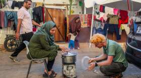 Wisal Abu Odeh and her husband cooking near their tent at a makeshift U.N. camp for displaced Palestinians in Khan Younis. (Samar Abu Elouf/New York Times)