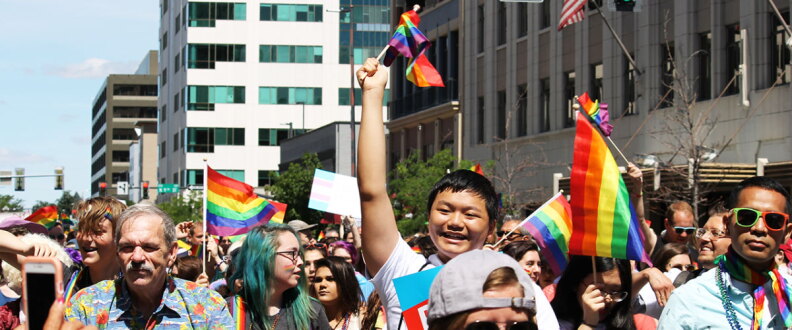People waving rainbow flags march the streets of downtown Boise during a Pride parade.