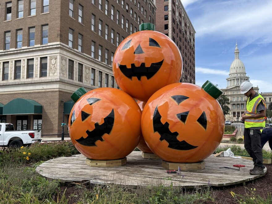 Large jack-o-lantern ornaments sit in front of the Michigan State Capitol