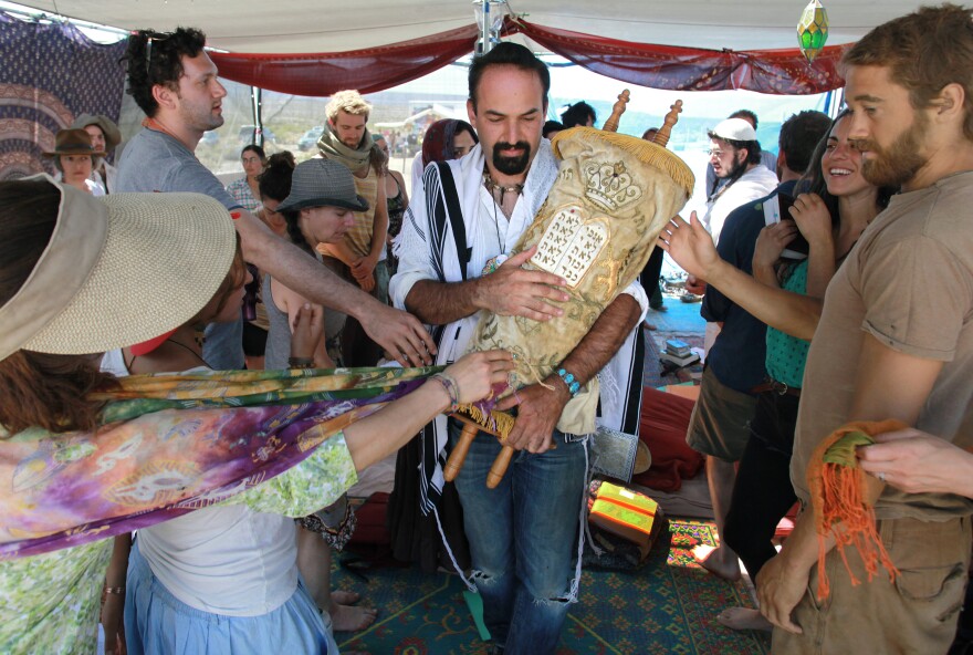 During a Saturday morning Shabbat service, Sagi Salomon carries a Torah scroll that survived the Holocaust through the Tent of Meeting. Touching the Torah cover appropriately is a symbolic way to show respect and affection for the Torah and the Jewish teachings it contains and represents.