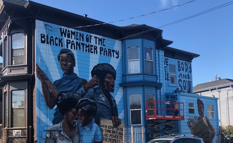 Side view of the mural of four black women on a victorian in West Oakland. The title reads "Women of The Black Panther Party."