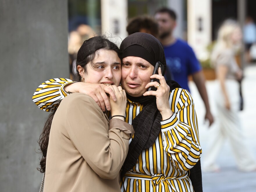 People evacuated from the Fields shopping center react, in Orestad, Copenhagen, Denmark, on Sunday after reports of shots fired.