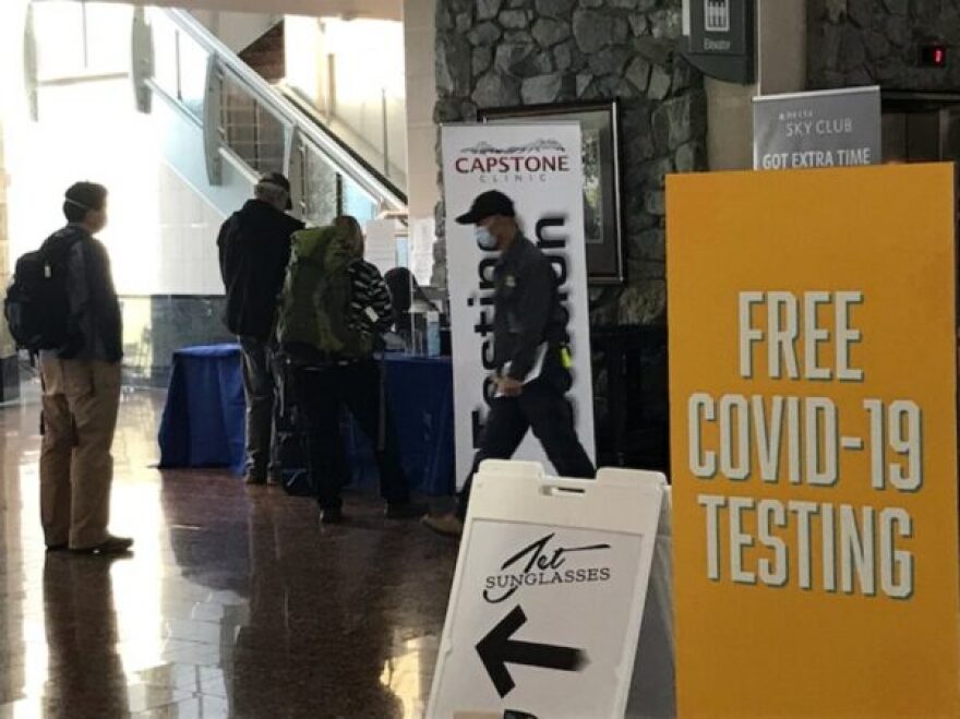 people with backpacks check in at a table below some stairs