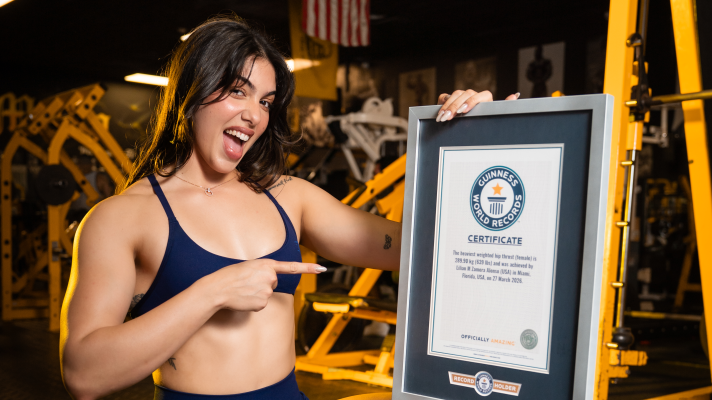 Lilian Zamora Alonso posing with the Guiness World Record certificate for heaviest weighted hip thrust by a woman.