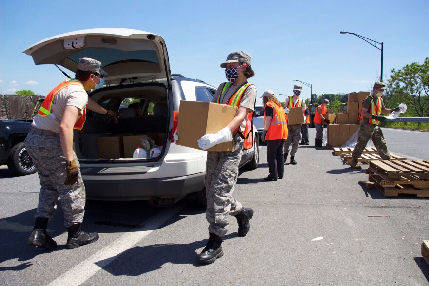 A volunteer with the Civil Air Patrol carries a box of MREs to a car