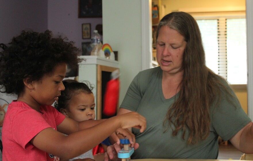 Liz Arnold interacts with two children (names withheld for privacy) at Just Like Mine Daycare in Lincoln, Nebraska, on July 22, 2026. She’s certified to care for up to 10 children in her home, but this summer she is taking care of six.