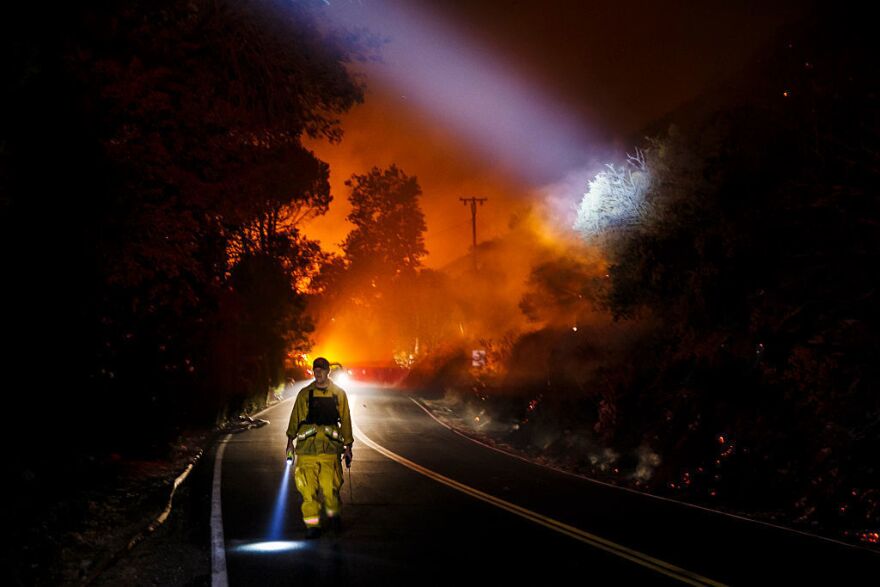 A firefighter point their beam lights around a burnt area to check for damages made by the Blue Cut fire.