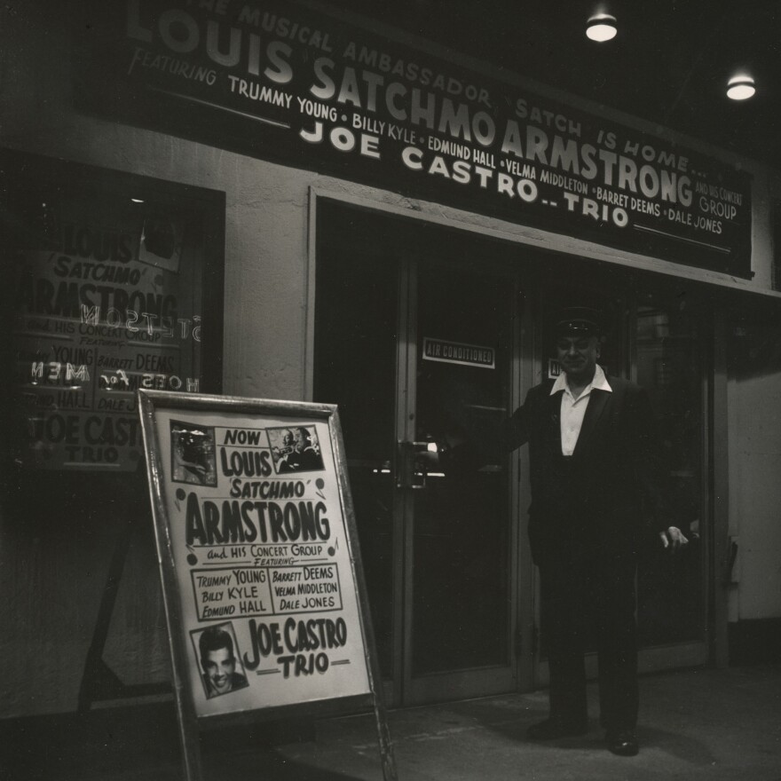 An usher stands with billboards advertising performances by Louis Armstrong and Joe Castro outside Basin Street in New York.