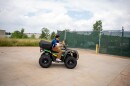 Man in blue shirt drives ATV in a parking lot.