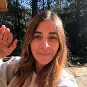 Woman waving and looking into camera.