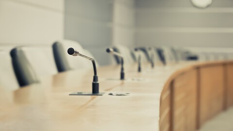 Empty line of seats and microphones with wooden table 