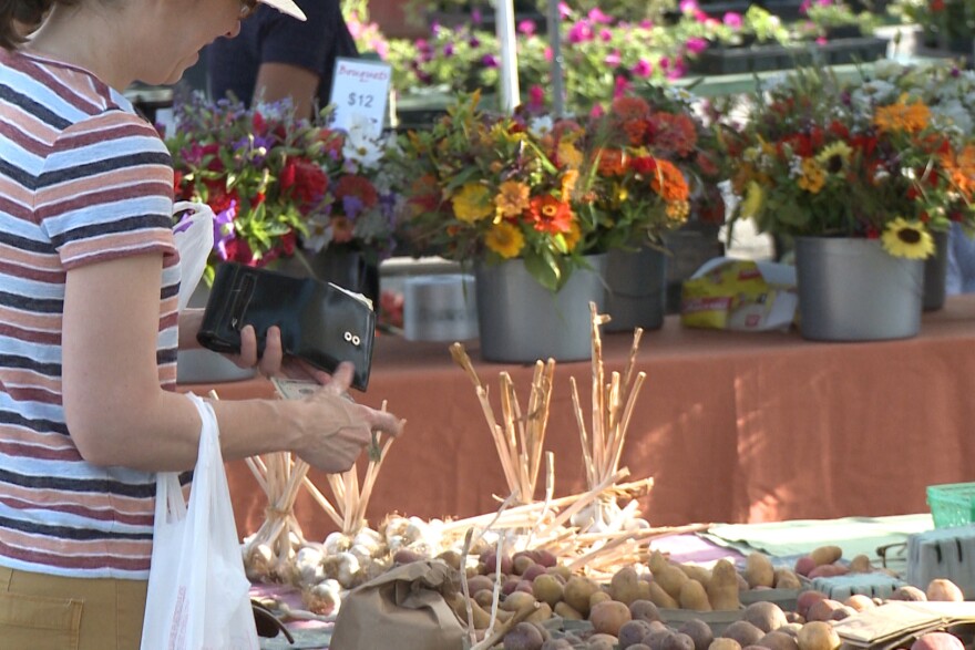 People shop at a farmers' market set up by Bloomingfoods