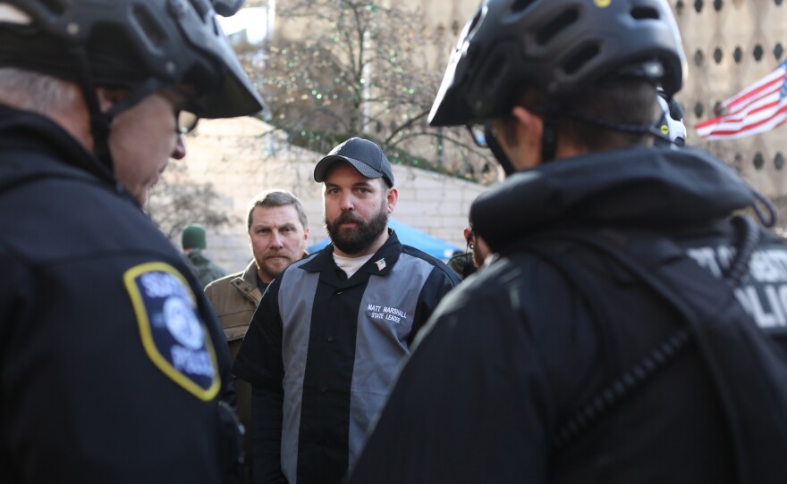 Matt Marshall, state leader of the Washington Three Percent, talks with law enforcement during the rally. He is trying to distance his group from the militia image.