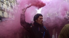 A protester holds a pink flare during a demonstration in Paris. (Aurelien Morissard/AP)
