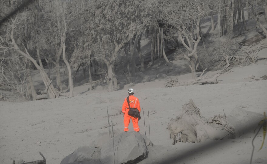 A firefighter is seen while he and other firefighters search for their missing colleague in the area affected by the volcanic eruption in Alotenango, Guatemala.