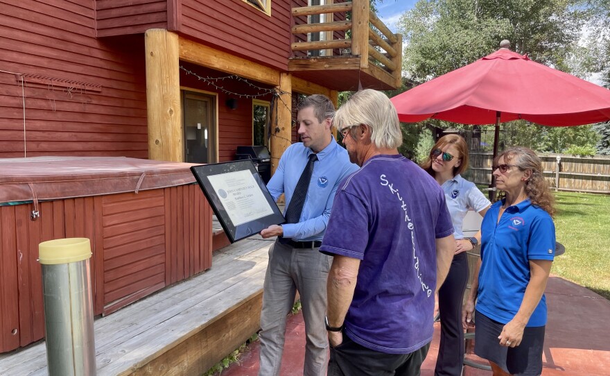 Van Cleave shows Lindon his award. Lindon also received an embroidered jacket, as well as a plaque and pin cooperative observers receive after every five years of observation.