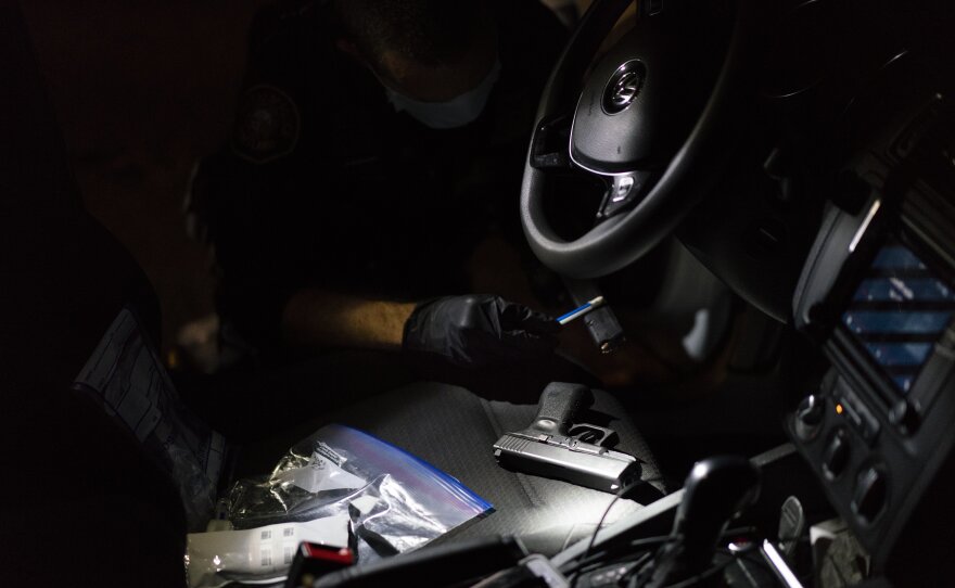 Officer Patrick Murphy swabs a handgun that he and gang enforcement officers found in a car with three people in front of a high school homecoming football game in Portland, Ore.