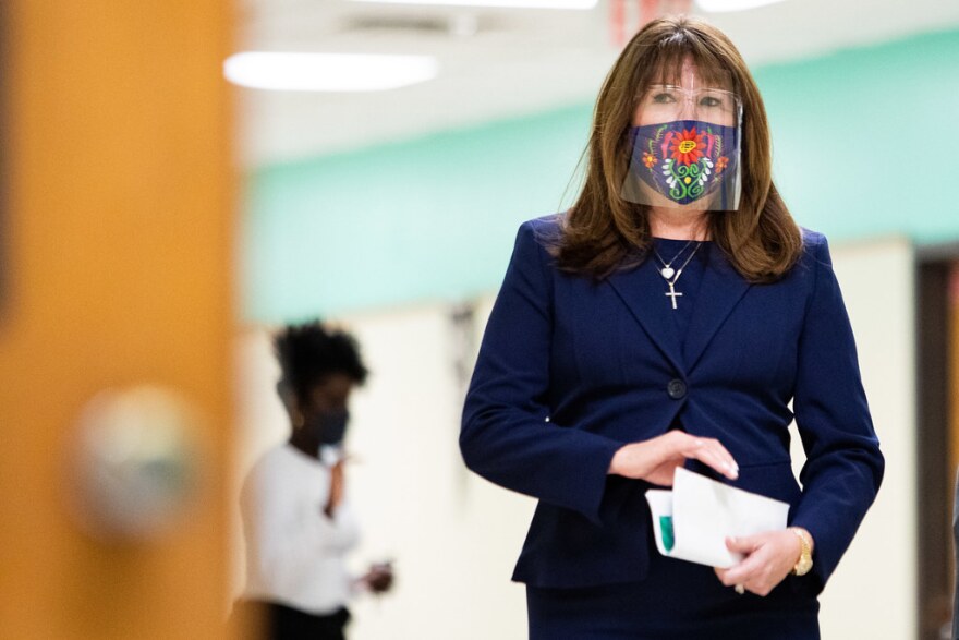 Superintendent Elizalde walks down the hallway of LBJ Early College High School wearing a face mask and face shield. 