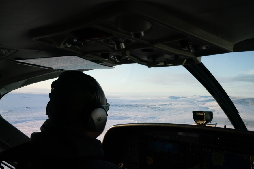 A RavnAir pilot guides a flight to Toksook Bay, Alaska, which can be seen out the window.