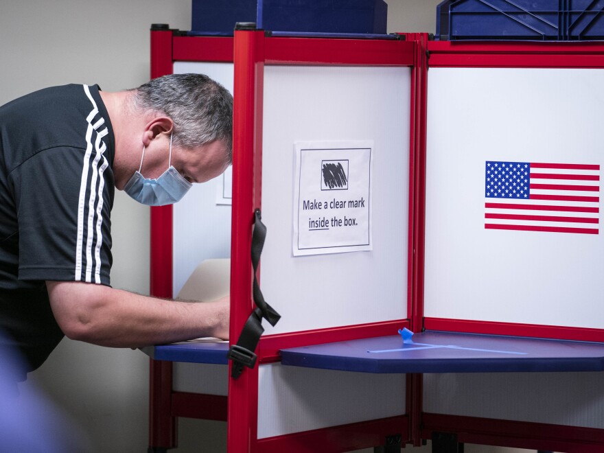A man casts his ballot for the 2020 presidential election at an early voting location in Alexandria, Va. Voters in Virginia will now be able to register until 11:59 p.m. on Thursday, in person or online.