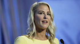 Primer plano de Bridget Ziegler mirando a lo lejos detrás de un micrófono, con un vestido amarillo