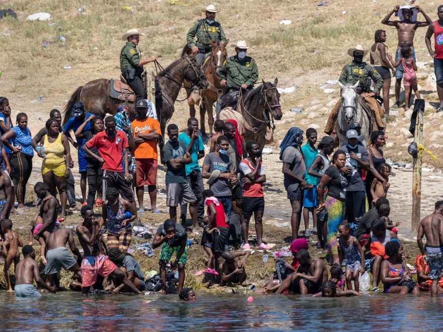 Mounted Border Patrol agents watch Haitian immigrants on the bank of the Rio Grande in Del Rio, Texas, as seen from Ciudad Acuña, Mexico.