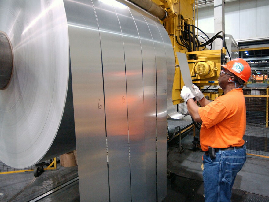 An employee inspects finished rolls of aluminum at an Alcoa facility in Newburgh, Ind., in 2006. The company has slashed payrolls in its core business by about one-third.