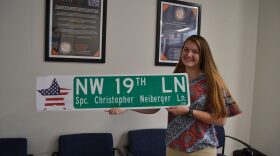 Abigail Islam displays an example of what street signs will look like with the added decal. It is aimed at making the signs more noticeable and therefore better honoring fallen service members and police officers. (Eve Rosen/WUFT News)