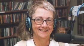 A woman posing for the camera behind a microphone with headphones on. 
