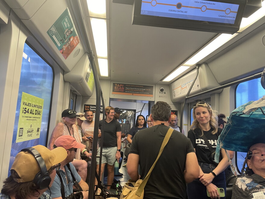 Crowd of people sit and stand on a light rail train